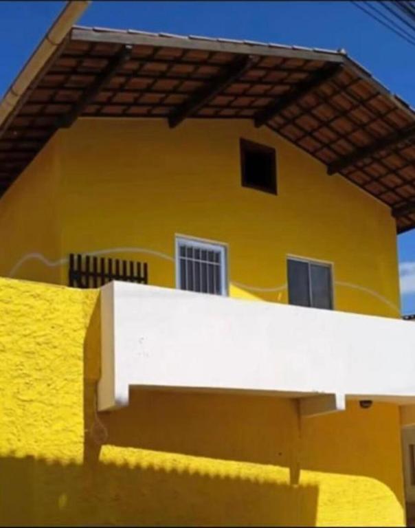 a yellow house with a white railing in front of it at Apartamento Amarelinho - Canoa Quebrada in Aracati