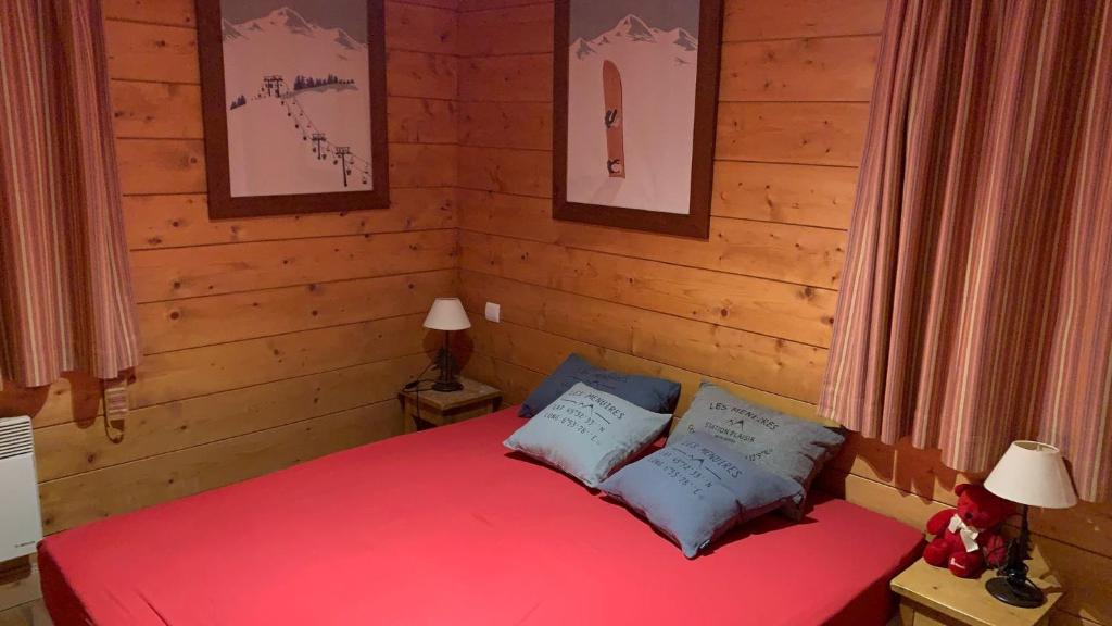 a bedroom with a red bed with two pillows at Appartement Airelles B19 in Levassaix