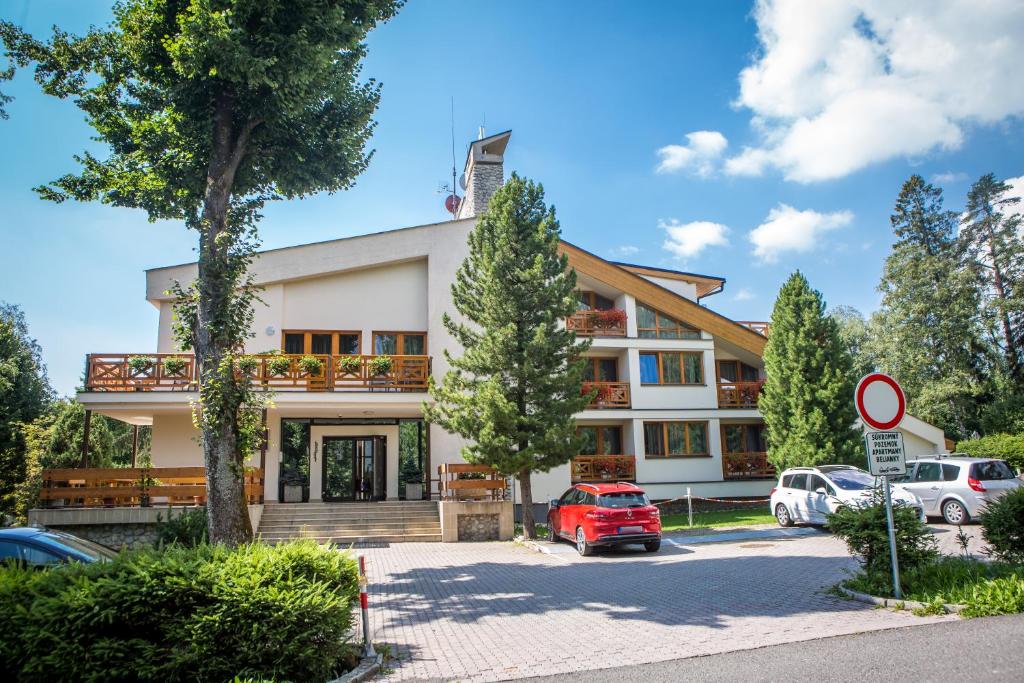 a building with cars parked in a parking lot at Apartmany Belianky in Vysoke Tatry - Tatranska Lomnica.