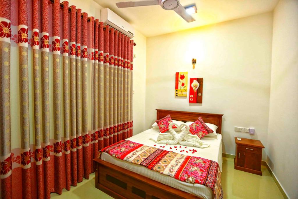 1 dormitorio con 1 cama con cortinas rojas en Orchidee Apartments en Mount Lavinia
