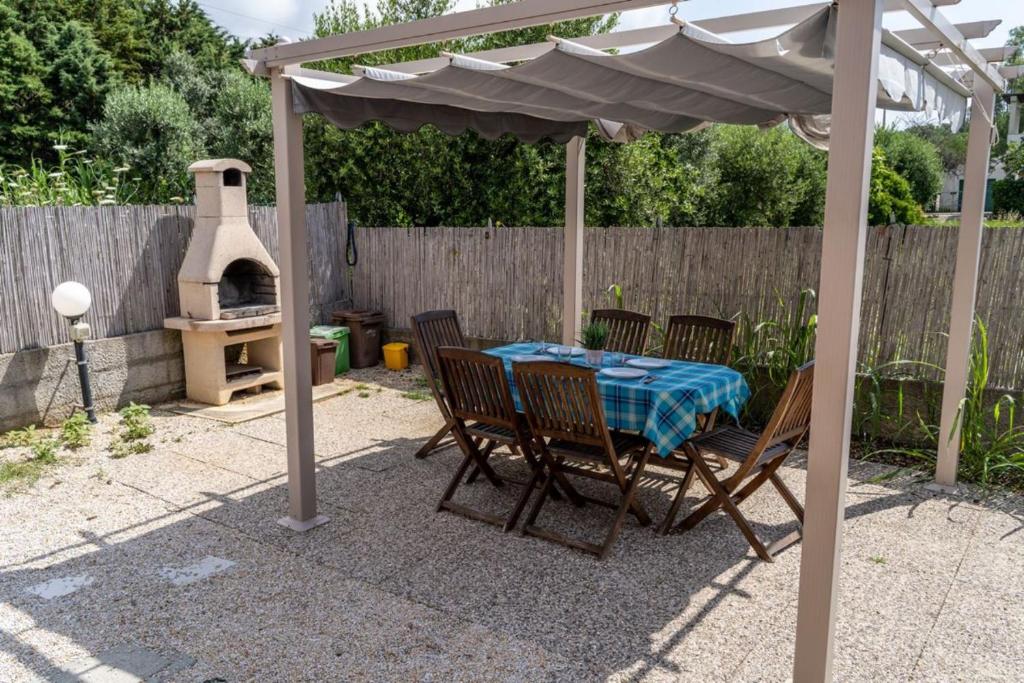 a table and chairs under an umbrella with a pizza oven at Golfo di Lacona in Lacona