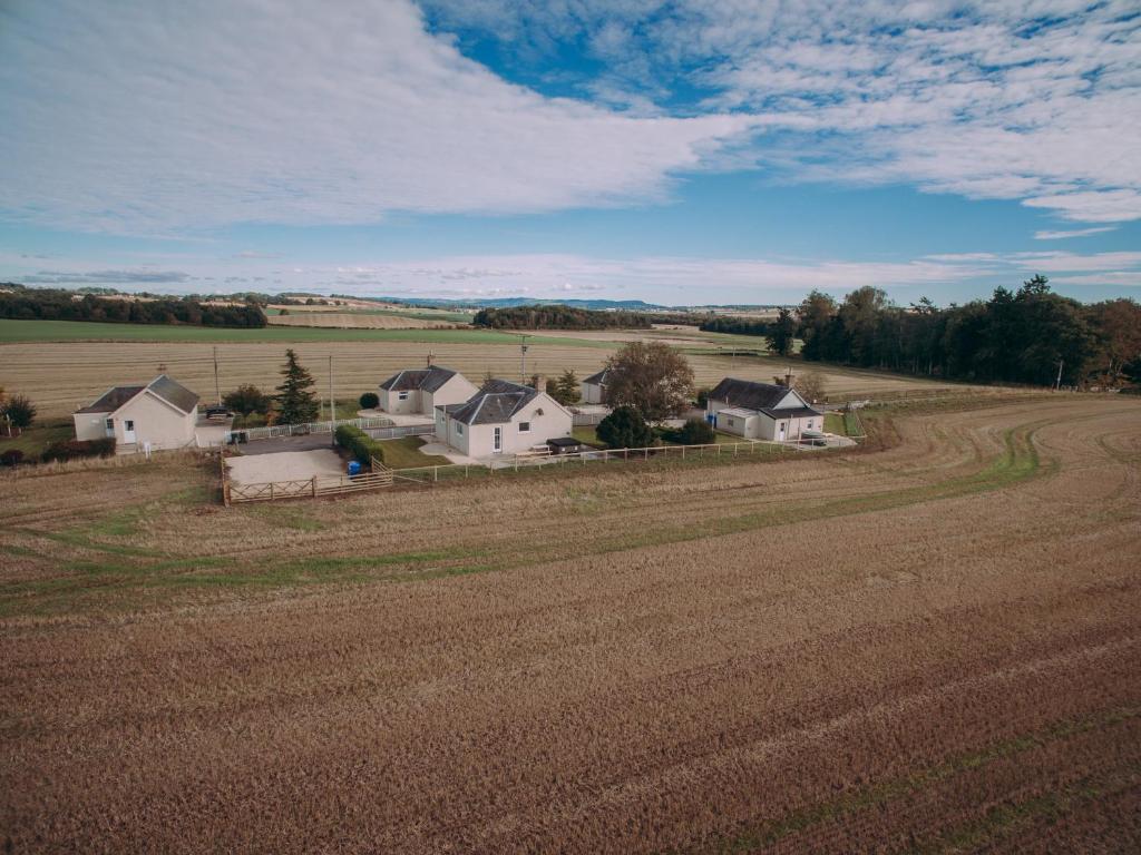 een boerderij met een veld en huizen in de verte bij Ninetrees - Uk47883 in Keilour