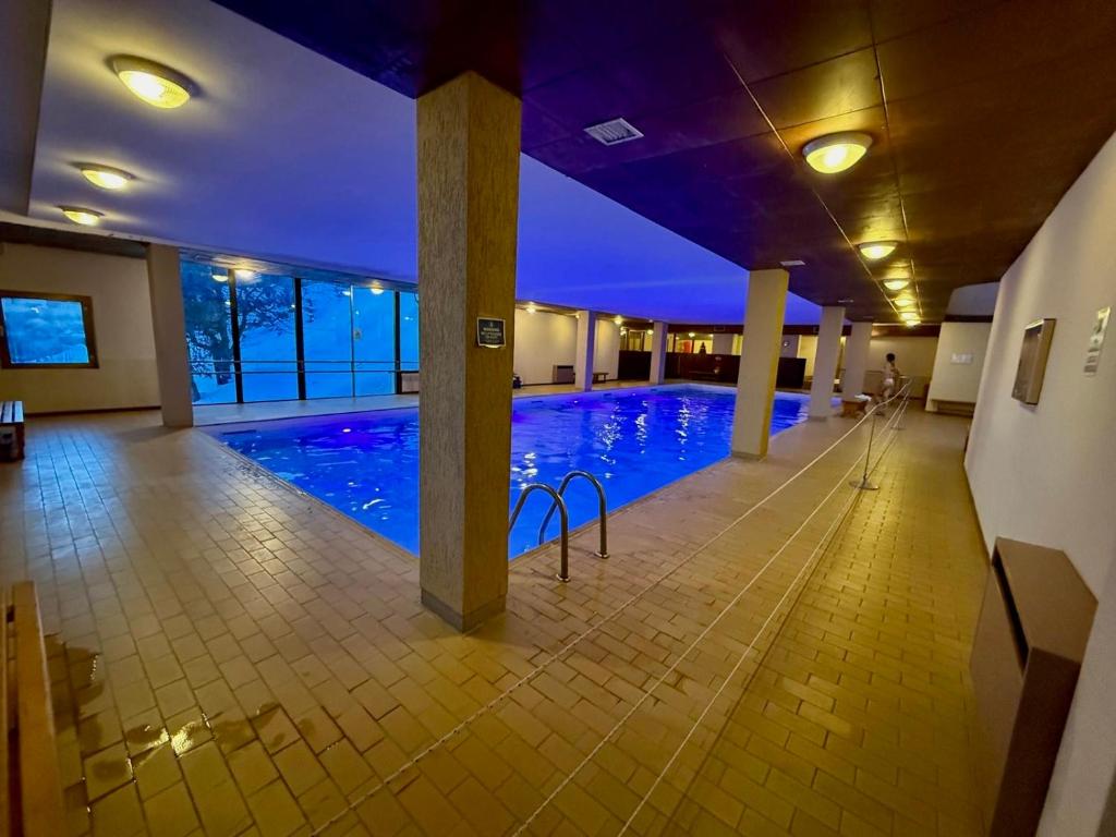 a large swimming pool with blue lights in a building at Top Residence Trilocale Larice in Passo del Tonale