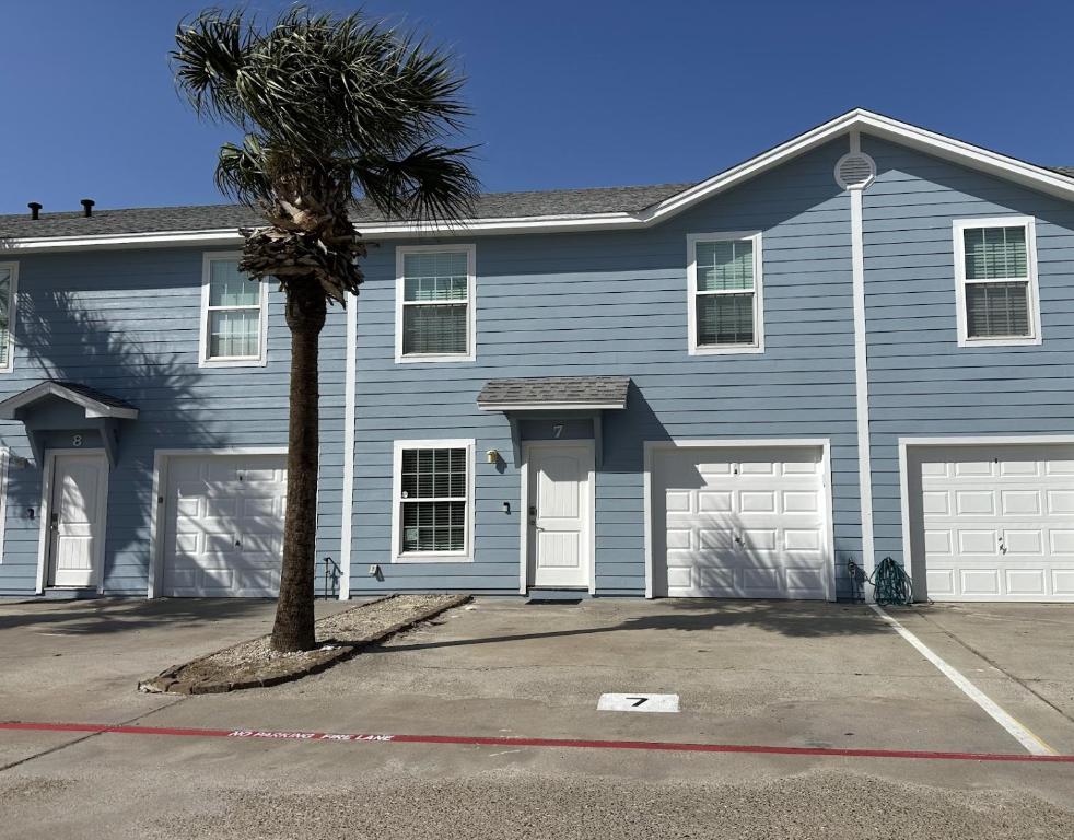 a blue house with a palm tree in front of it at The Beach Peach in Port Aransas