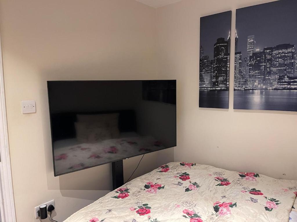 een slaapkamer met een bed en twee schilderijen aan de muur bij One Bedroom Flat in London Heathrow 20 minutes drive in Greenford