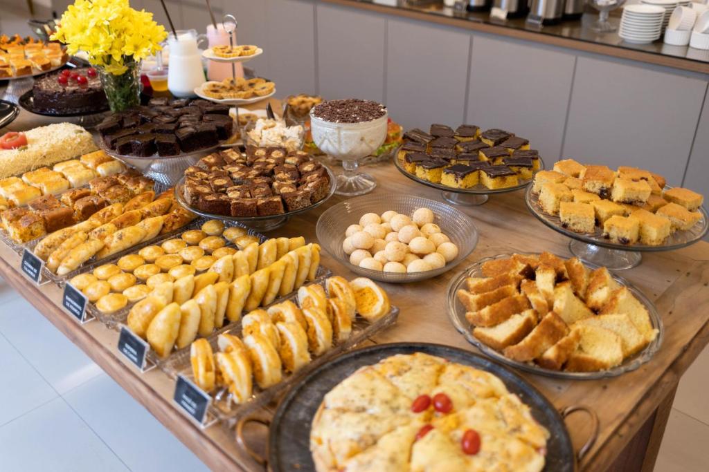 a table filled with different types of pastries and pies at Hotel Pedra Negra Gov. Valadares in Governador Valadares
