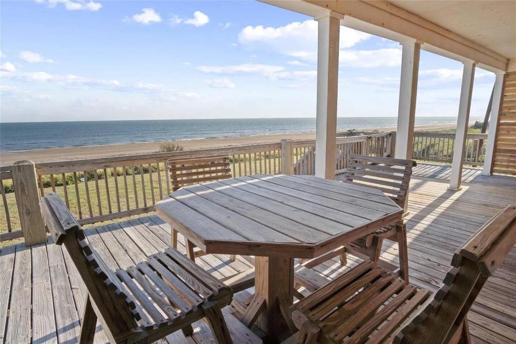 a wooden table and chairs on a deck with the beach at Beachfront Home with Huge Deck in Bolivar Peninsula