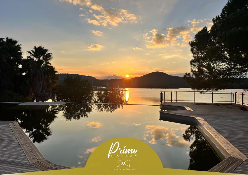 een zonsondergang boven een waterlichaam met een dok bij Casa 115 - Plage & piscine chauffée in Pianottoli-Caldarello