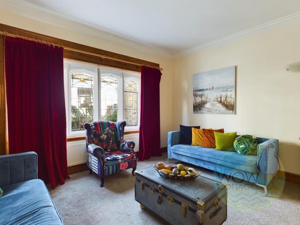 un soggiorno con tende rosse e un divano blu di Haslemere - Beer Devon a Beer