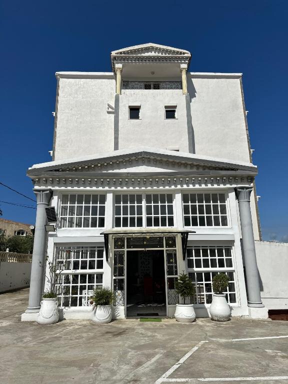 a white building with white columns and windows at Résidence Les Camélias in Tabarka