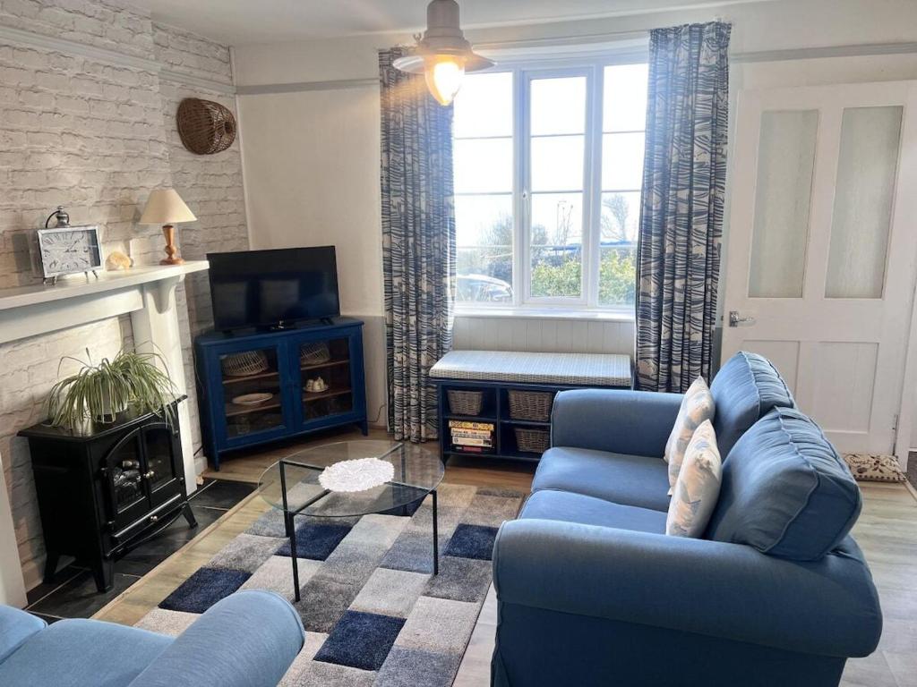een woonkamer met een blauwe bank en een open haard bij Seaview Terrace - Beer in Beer