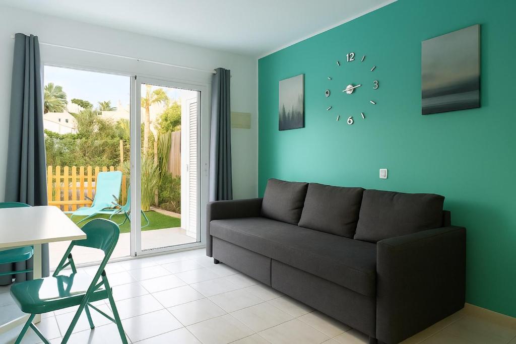 ein Wohnzimmer mit einer Couch und einer Uhr an der Wand in der Unterkunft Maspalomas Green Oasis 1404 in Maspalomas