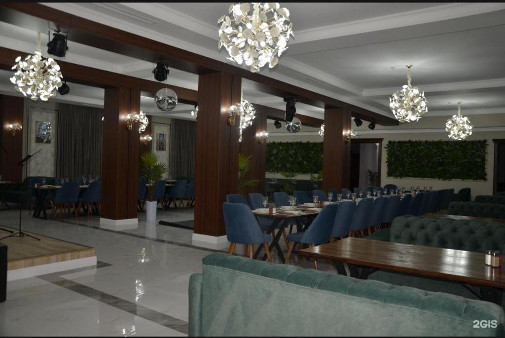 a banquet hall with blue chairs and tables and chandeliers at Tour House in Tridtsatʼ Let Kazakhstana