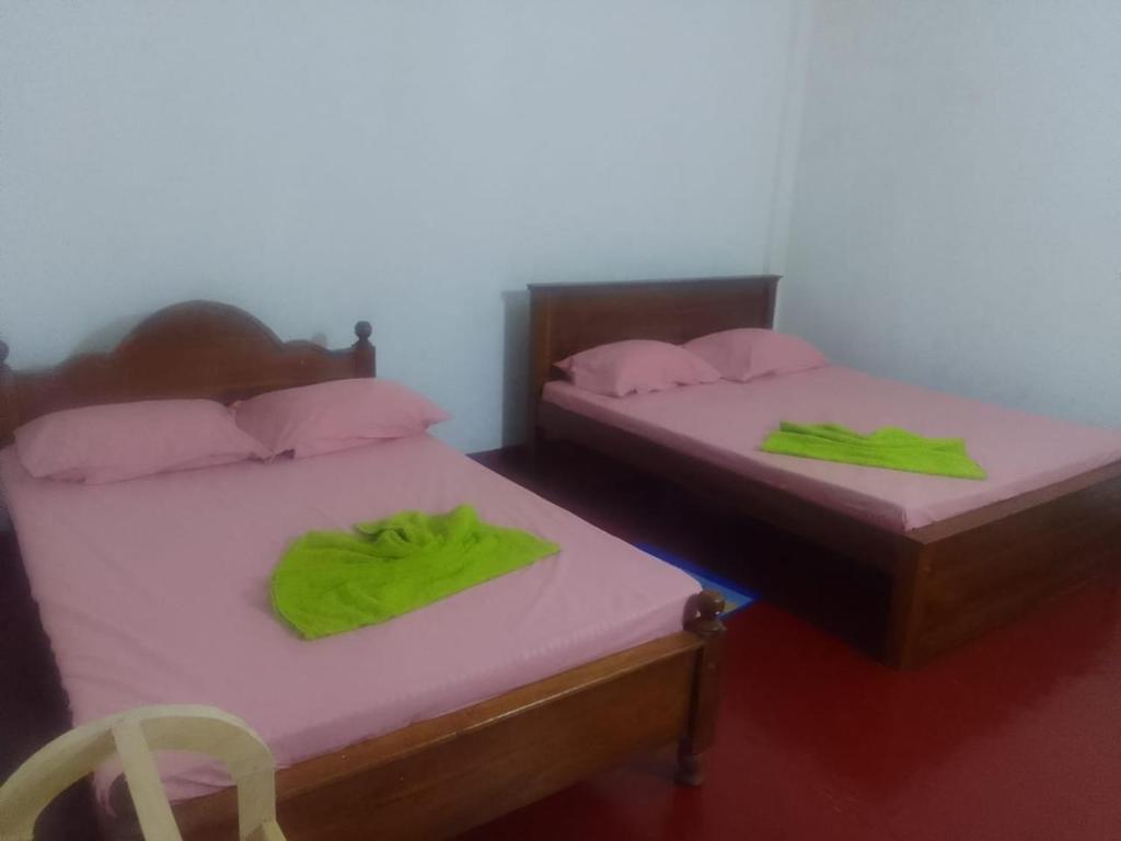 twee bedden in een kamer met groene handdoeken erop bij Madura Resorts in Piliyandala
