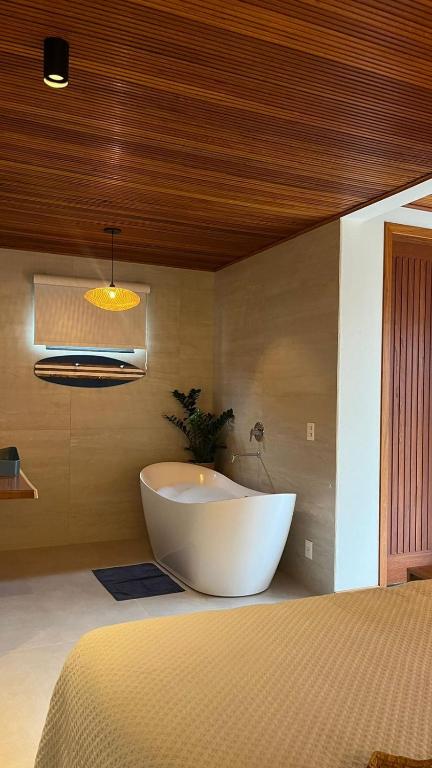 a large white tub in a room with a bed at Recanto Gamboa in Garopaba