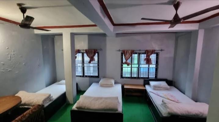 a room with three beds and two windows at Baglung Durbang Guest House in Pokhara