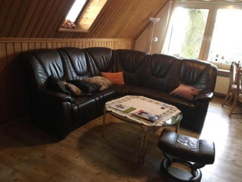een zwarte leren bank in een woonkamer met een tafel bij Ferienhaus am Holzendorfer See in Dabel