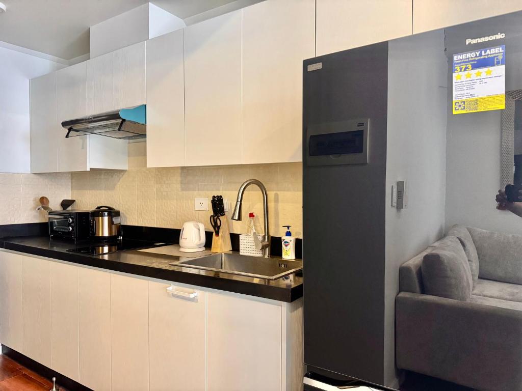 una cucina con armadi bianchi, lavandino e divano di Chic Units at Ivory Residences a Davao