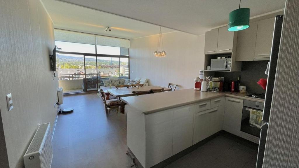 a kitchen with a table and a dining room at Departamento Costa Pucón in El Cerrillo