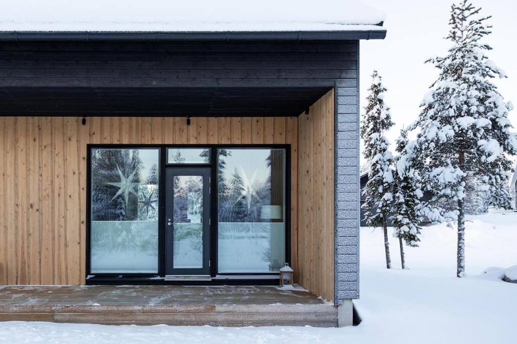 a house with glass doors in the snow at Villa Aurora Noir in Rovaniemi