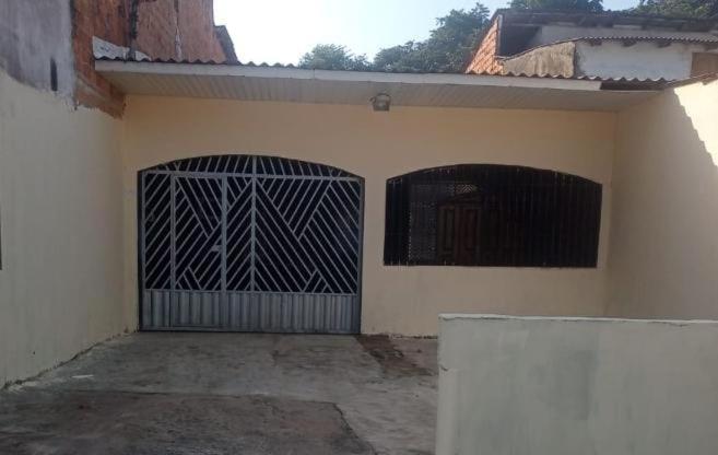 a house with a gate and a building at Casa 2 quartos em frente a praia na cidade mística de colares a 96 quilômetros de Belém do Pará in Colares