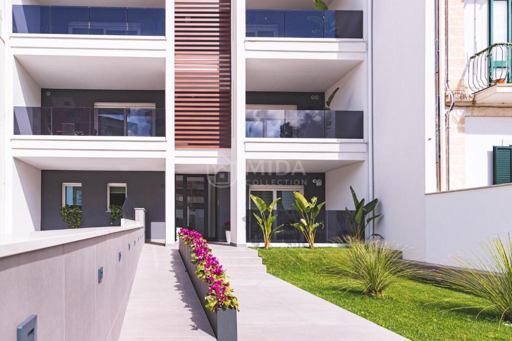 een gevel van een wit appartementencomplex met paarse bloemen bij VITTO Luxury Apartment in Lecce