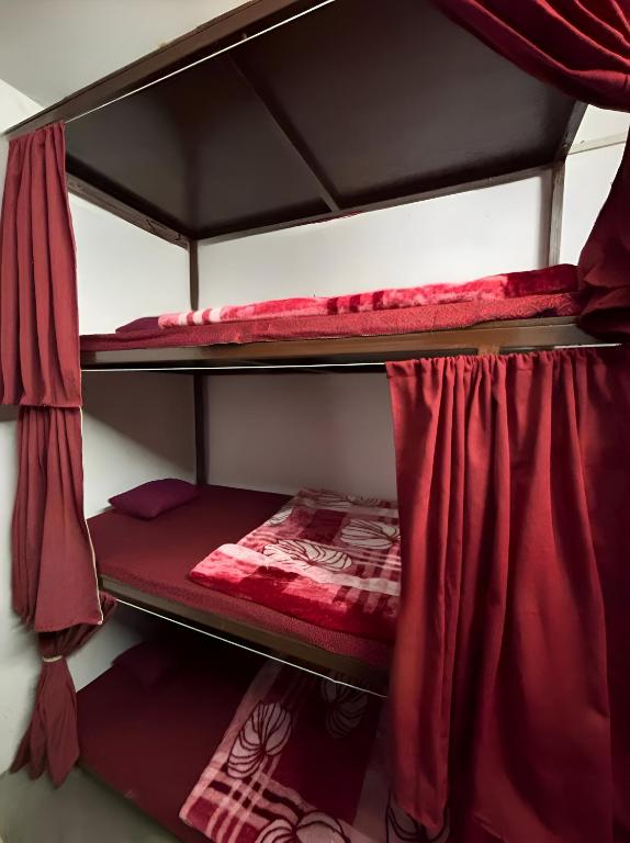 two bunk beds in a room with red curtains at Shivanand Aashray - Near Sangam in Prayagraj