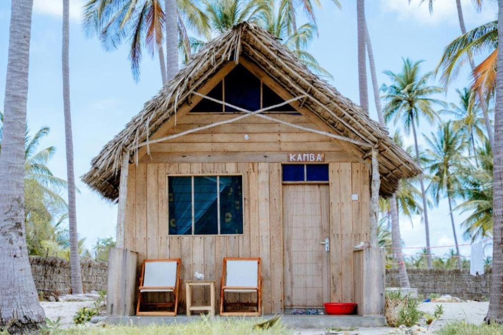 eine kleine Hütte mit zwei Stühlen und Palmen in der Unterkunft Quiet beachfront hideaway - Mafia Island - 2355 in Bweni