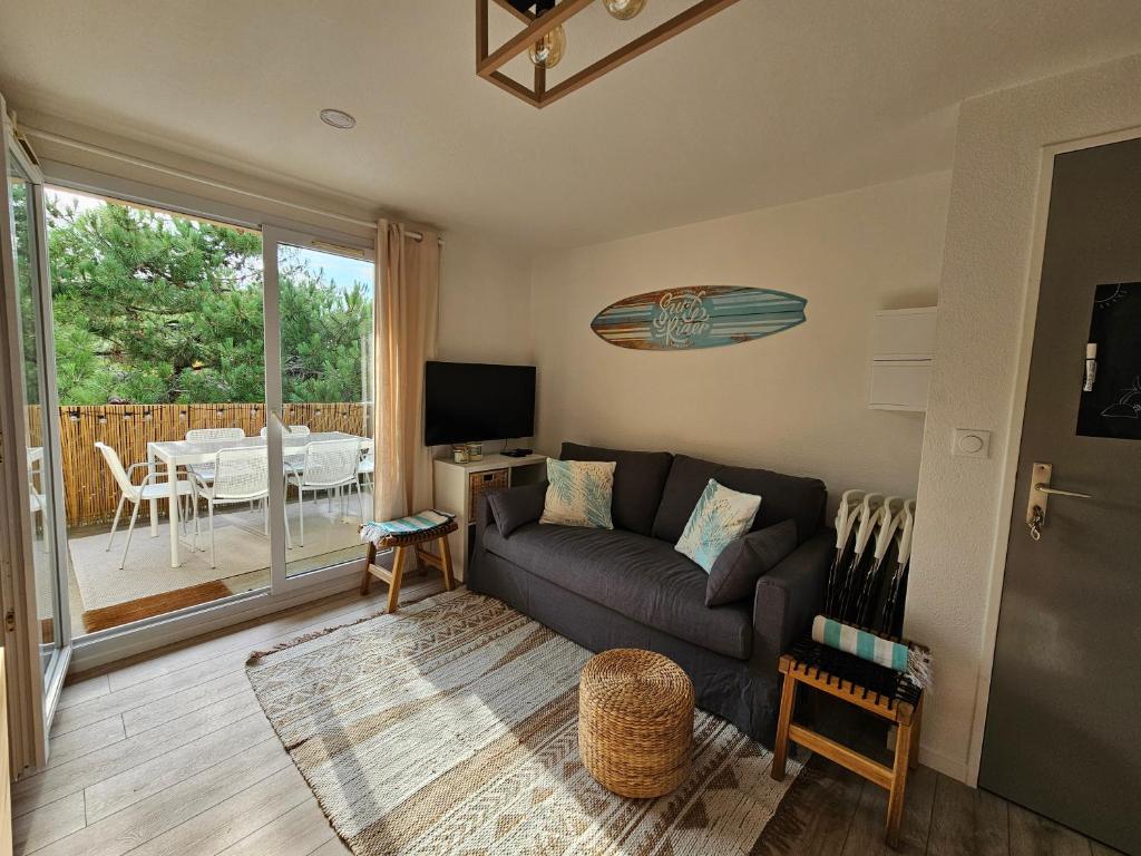 ein Wohnzimmer mit Sofa und Tisch in der Unterkunft Cocon Les Pieds dans l'Eau- Les Hameaux de l'Océan in Carcans