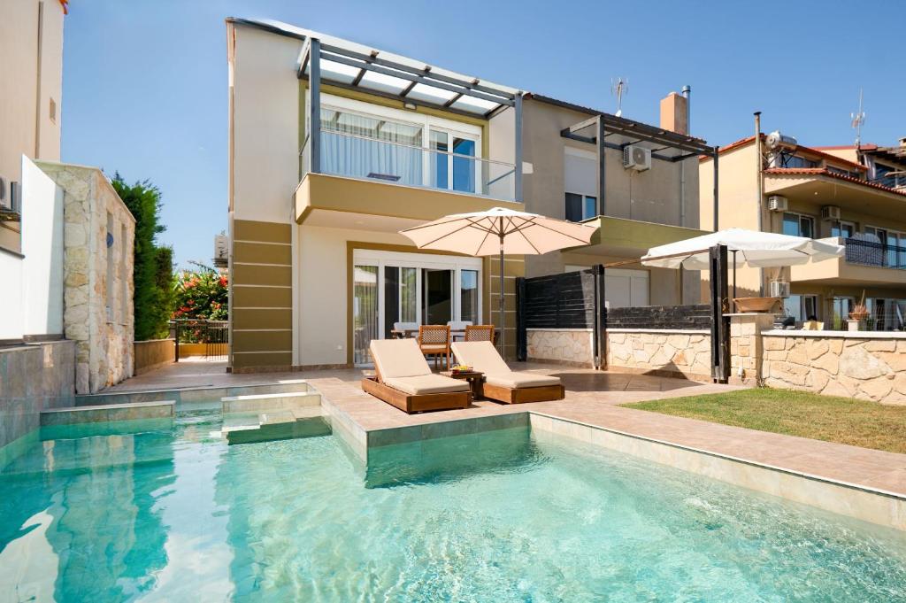 een zwembad met stoelen en parasols naast een huis bij Spa Villa Sunny in Hanioti