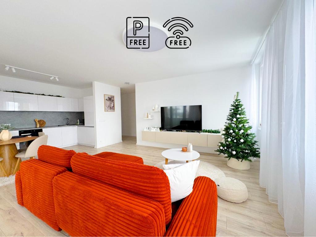 een woonkamer met een oranje bank en een kerstboom bij A2 Severna Apartment, near City Center and High Tatras in Poprad