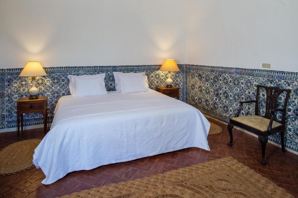 een slaapkamer met een groot wit bed en een stoel bij Palácio Ficalho in Bicas
