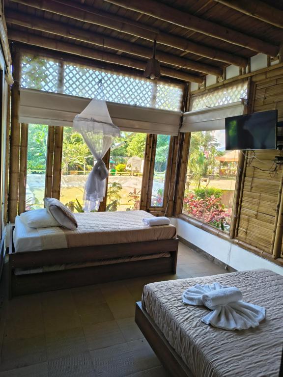 La SerenaにあるHOTEL Casa del Árbol ECOPARQUE CHINAUTAのベッドルーム1室(ベッド2台、テレビ付)