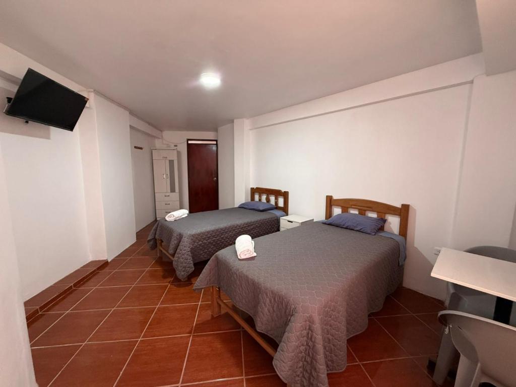 a room with two beds and a television in it at Hostal La Reserva - Pisco in Pisco