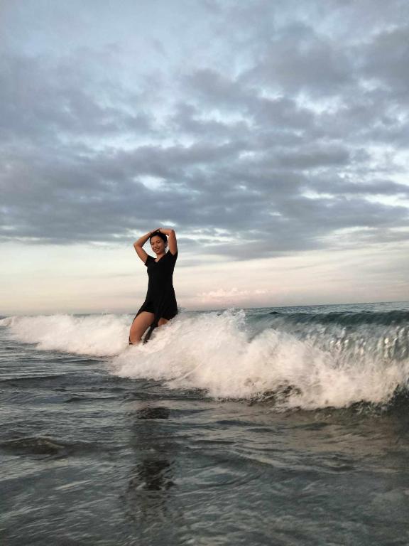 a woman standing on a surfboard in the ocean at Native Rooms in Luna