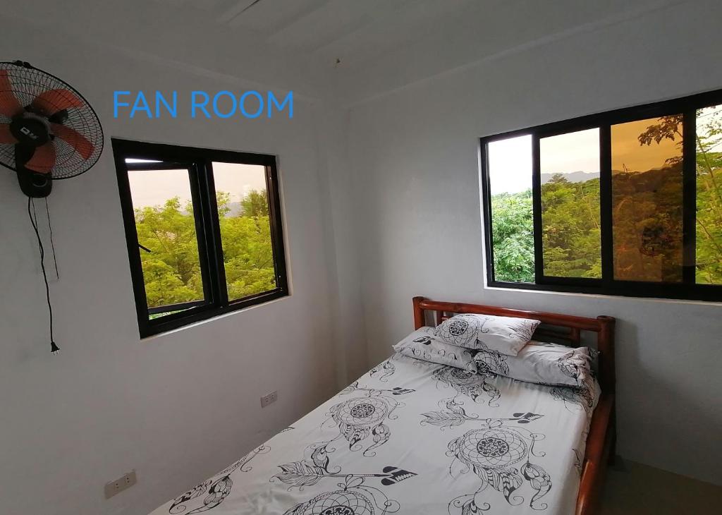 ein Schlafzimmer mit einem Bett mit Ventilator und Fenstern in der Unterkunft Uncle Bob & Tere Beach House in Luna
