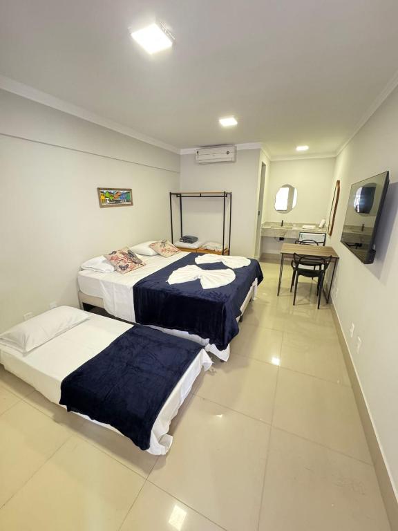 a room with two beds and a table with a tableablishthritisthritisthritisthritis at Orla Suítes in Porto Seguro