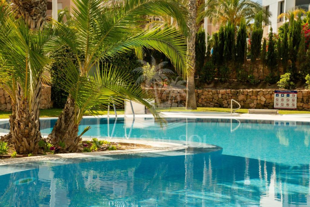 a large swimming pool with palm trees and a building at Sunny Place Oasis del Sol in Arenales del Sol