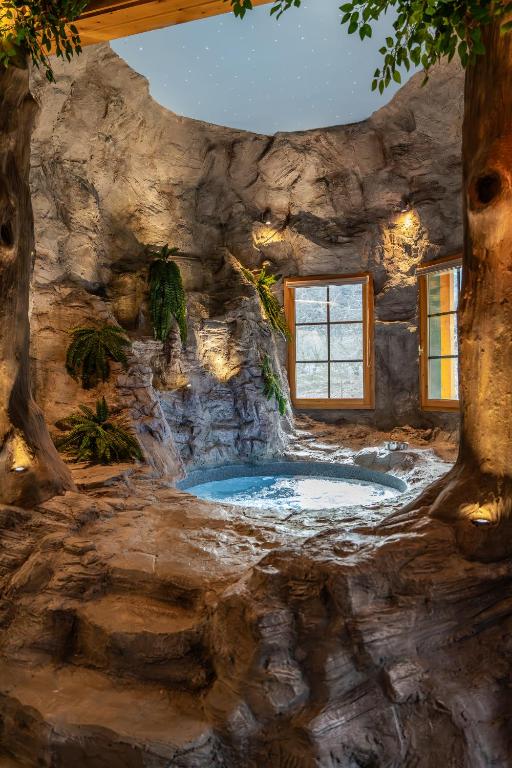 a stone walled room with a jacuzzi in a rock wall at Cave Chalet - Waterfall Chalet in Eptalofos