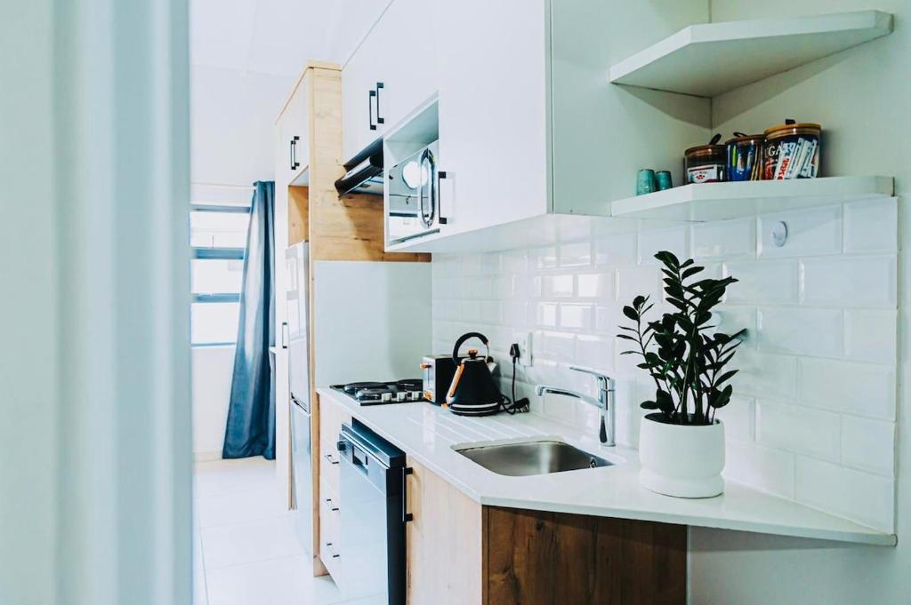 a white kitchen with a sink and a potted plant at Modern Nest in Sandton