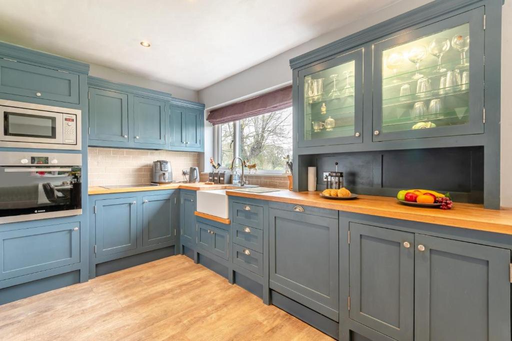 een keuken met blauwe kasten en een houten vloer bij 5 Bed in Utterby oc-t34067 in Fotherby