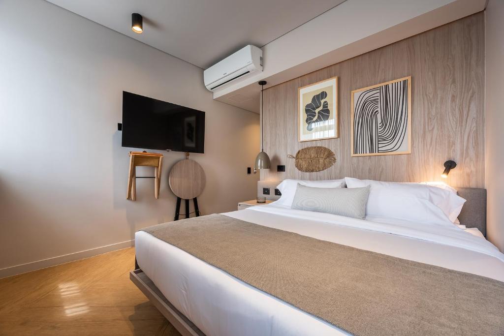 Un dormitorio con una gran cama blanca y un televisor de pantalla plana. en Nakúa Stay & Work Hotel, en Medellín