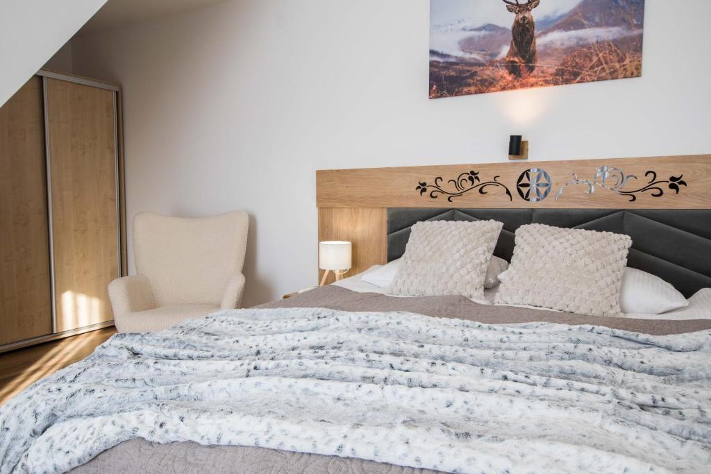 een slaapkamer met een groot bed en een stoel bij Apartamenty i Pokoje Gościnne U Trebuni in Murzasichle