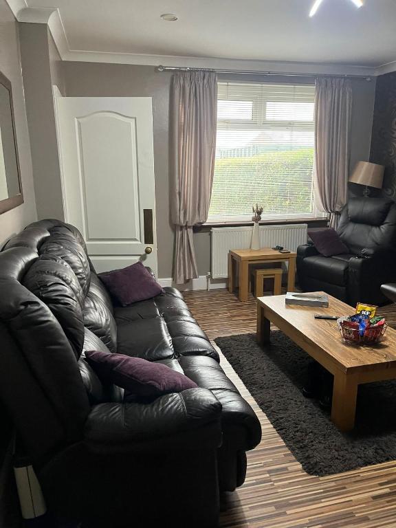 een woonkamer met een leren bank en een salontafel bij Rowan in Bellshill