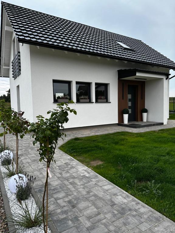 een wit huis met ramen en een gazon bij Dom "Między jeziorami" na Kaszubach, 10 osób, jacuzzi, ognisko, kominek in Grabówko
