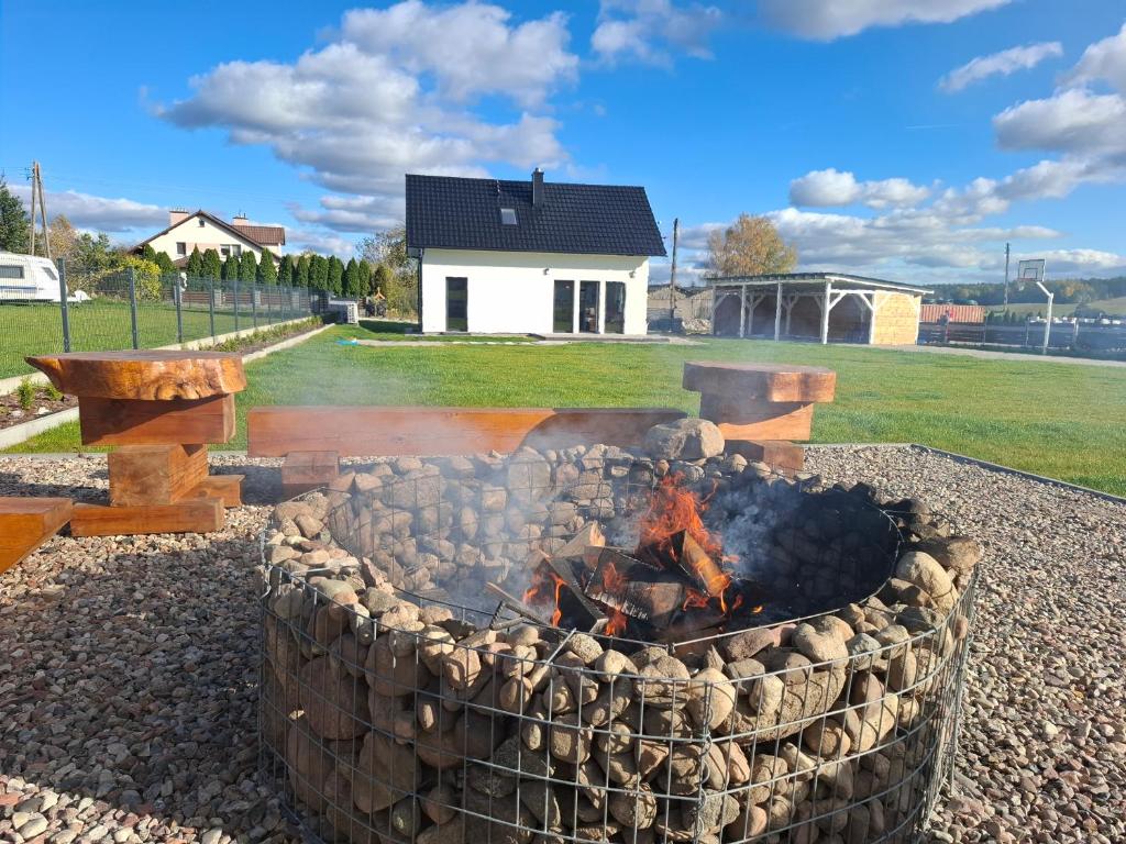 eine Feuerstelle in einem Hof mit einem Haus im Hintergrund in der Unterkunft Dom "Między jeziorami" na Kaszubach, 10 osób, jacuzzi, ognisko, kominek in Grabówko