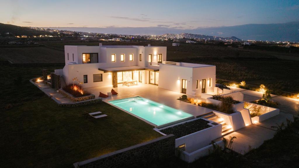 a large white house with a swimming pool at night at Santorini Vinery Mansion in Éxo Goniá