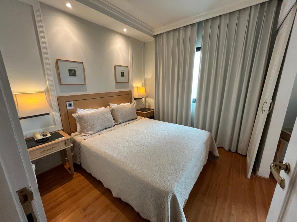 a bedroom with a large white bed and a window at Flat Hotel Pamplona Jardins Univer com garagem 2402 in Sao Paulo
