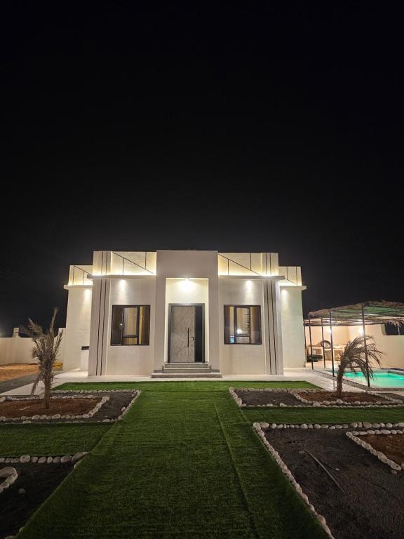 een groot wit huis met een gazon in de nacht bij Sinkhole Chalet in Bimmah