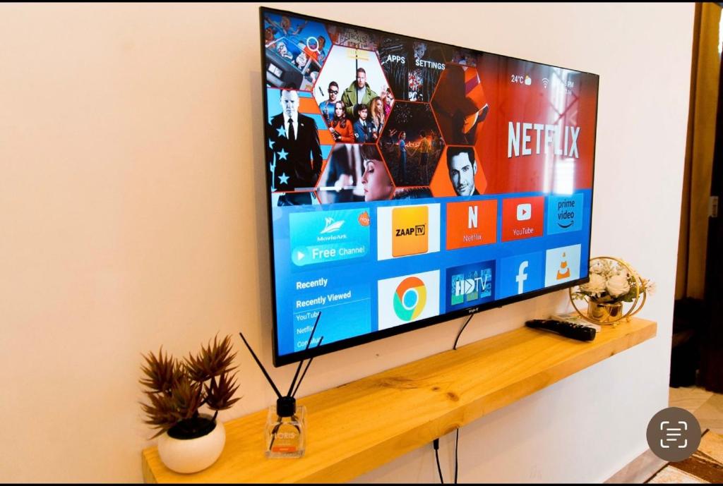 a flat screen tv sitting on a wooden shelf at Lumora Deluxe Apartment in Tanga